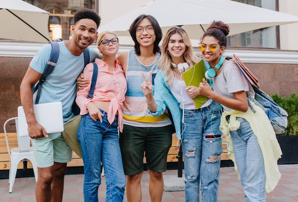 laughing-asian-boy-glasses-shorts-embracing-charming-blonde-girls-front-outdoor-cafe-joyful-students-came-open-air-restaurant-celebrate-end-exams-min