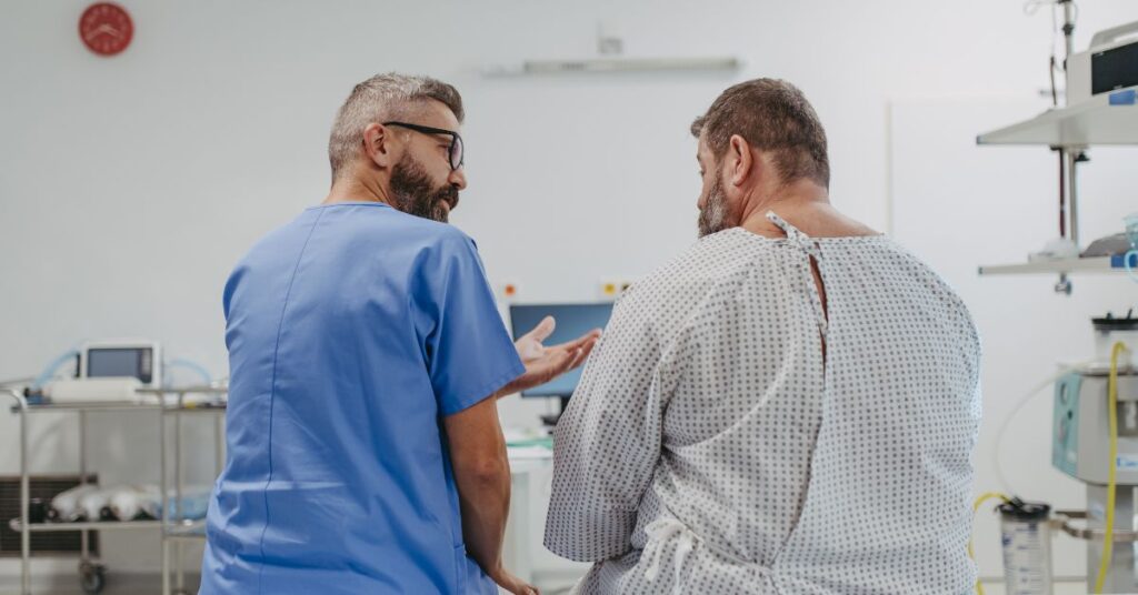 Homem obeso com uma camisola médica, ao lado de um médico conversando. Ao fundo, vemos que estão em uma clínica médica.